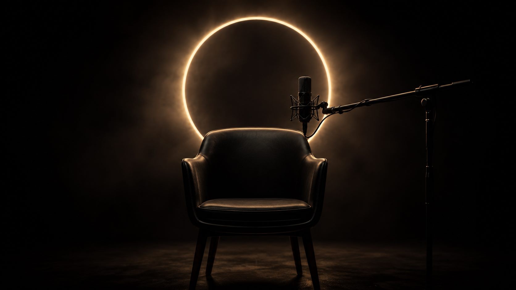 Un fauteuil d'entretien vide et un microphone, devant un anneau de lumière semblable à une éclipse.
